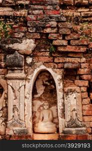 Sitting Buddha encarved in stone with bricks. Sitting Buddha encarved in stone with bricks and plants surrounding him