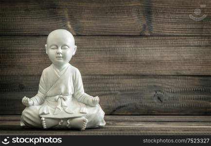 Sitting buddha. White statue on wooden background. Relaxing concept. Vintage style toned