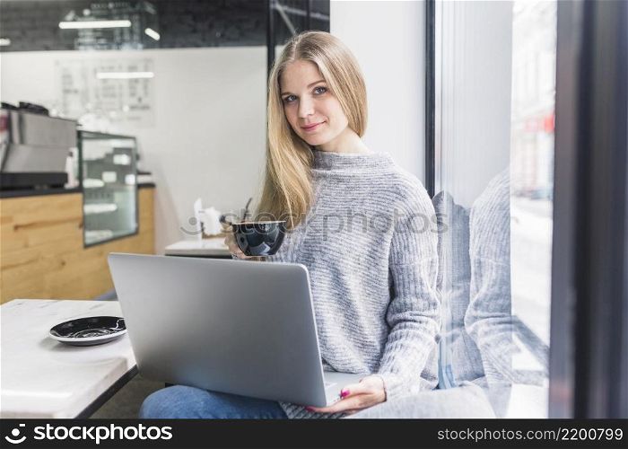sitting cafe woman using laptop holding cup