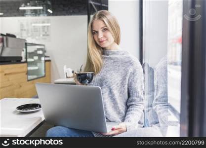sitting cafe woman using laptop holding cup