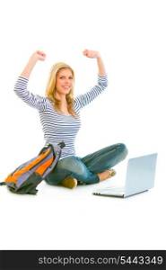 Sitting on floor with schoolbag and laptop pleased teengirl rejoicing her success isolated on white &#xA;