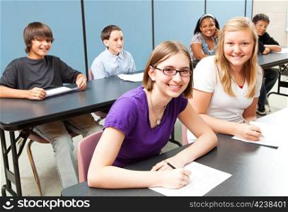 Six adolescent school children sitting at tables in class.