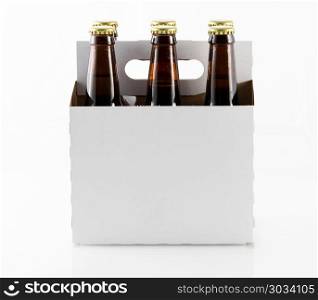 Six bottles of beer in cardboard carrier. Six beer bottles in cardboard container with gold caps with side of carrier facing camera. Six bottles of beer in cardboard carrier