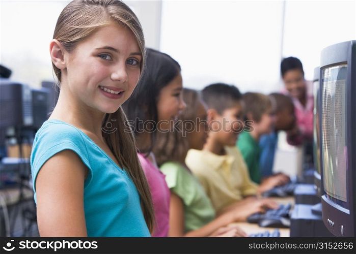 Six children at computer terminals with teacher in background (depth of field/high key)