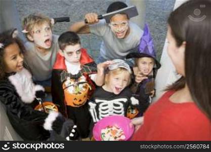Six children in costumes trick or treating at woman&acute;s house