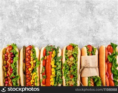 Six different hot dogs on a gray table, top view. Copyspace