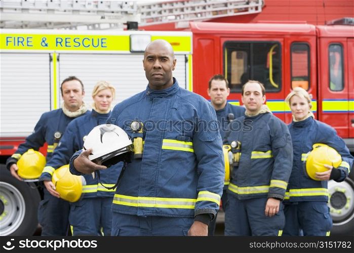 Six firefighters standing by fire engine