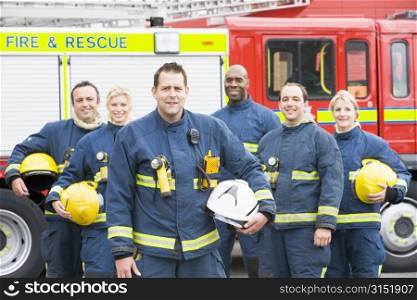 Six firefighters standing by fire engine