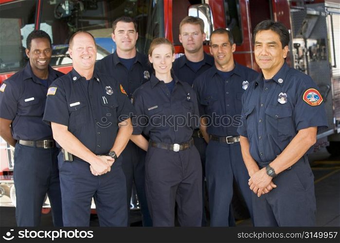 Six firefighters standing in front of fire engine with captain (depth of field)