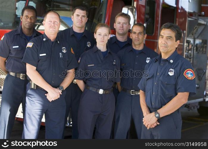 Six firefighters standing in front of fire engine with captain (depth of field)