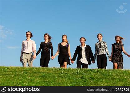 Six friends go on meadow having joined hands