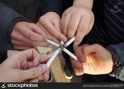 six hands of teens with cigarettes close by
