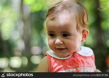 Six months old baby girl smiling outdoors.. Close-up portrait of six months old baby girl smiling outdoors with defocused background.
