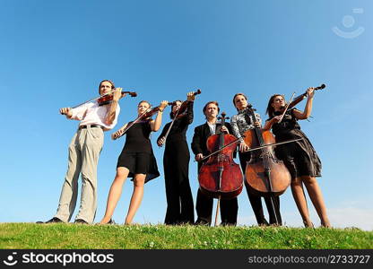 Six musicians play violins against sky, wide angle