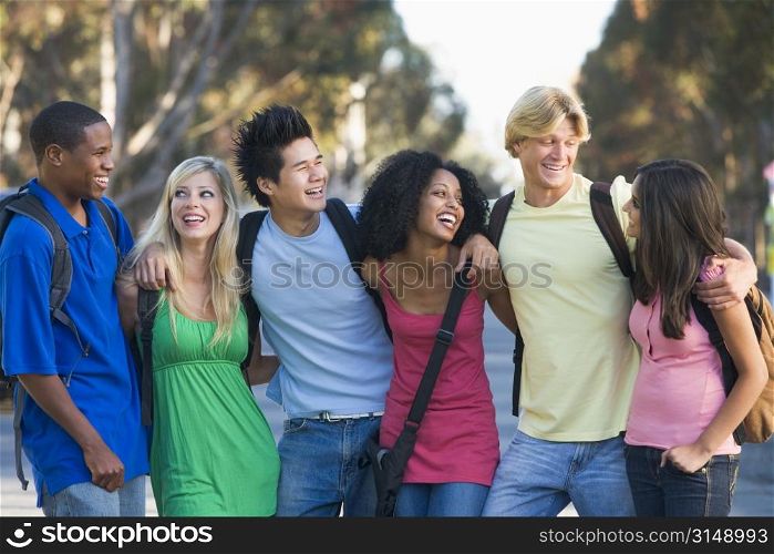 Six people outdoors standing arm in arm together (selective focus)