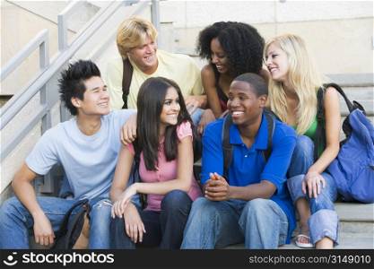 Six people sitting on staircase outdoors smiling