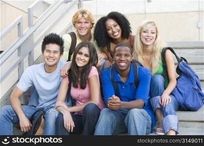 Six people sitting on staircase outdoors smiling