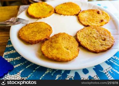 Six rounded delicious potato pancakes on white plate. Detailed food close up.. Six potato pancakes