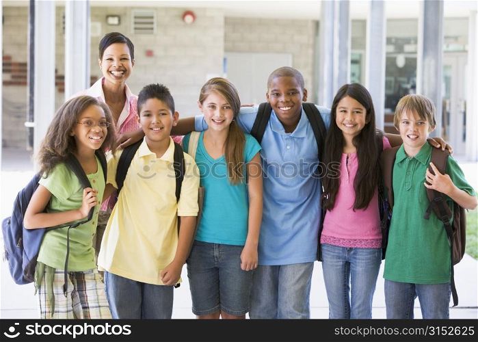 Six students standing outside school with teacher