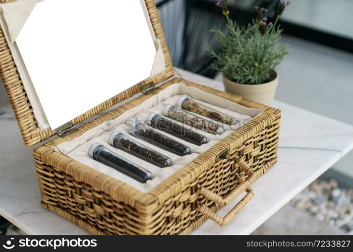 Six tube of different leaf teas collection in wicker basket.