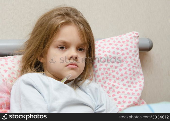 Six-year diseased girl sitting in bed and will measure the temperature of the thermometer