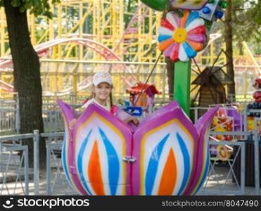 Six-year girl riding on a carousel, sitting in a stylized floret