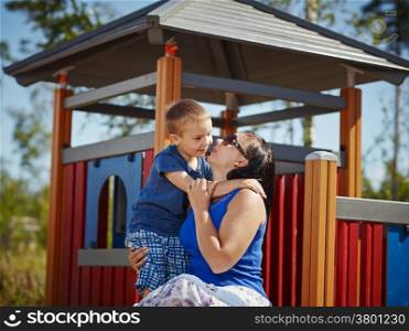 Six year old boy hug his mom, playground on background