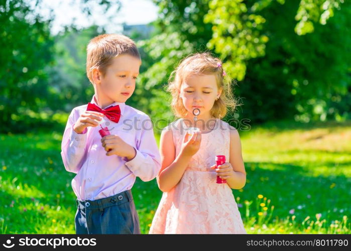six year old boy looks at the girl makes soap bubbles