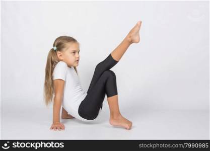 six year old girl aspiring gymnast performs a number of training exercises. An aspiring gymnast trying to pull his left foot resting on the hands and fingers of the right foot