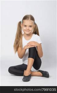 six year old girl aspiring gymnast performs a number of training exercises. Girl gymnast sitting on the floor