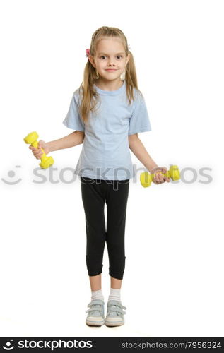 Six year old girl athlete engaged in exercise with dumbbells. Four-year girl Europeans engaged in physical exercises