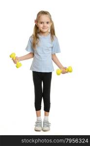 Six year old girl athlete engaged in exercise with dumbbells. Four-year girl Europeans engaged in physical exercises