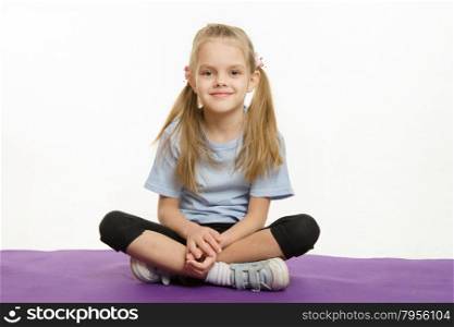 Six year old girl athlete sitting on a rug. Six year old girl sitting on the Europeans sports rug