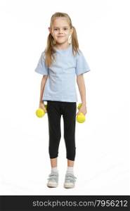 Six year old girl athlete standing with dumbbells. Four-year girl Europeans engaged in physical exercises
