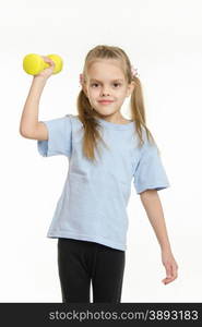 Six year old girl Europeans engaged in physical exercises. The girl raised her right arm dumbbell