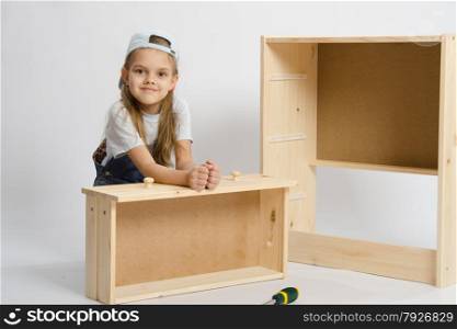 Six year old girl playing and collecting wooden cabinet. The child sits with a skeleton chest and box