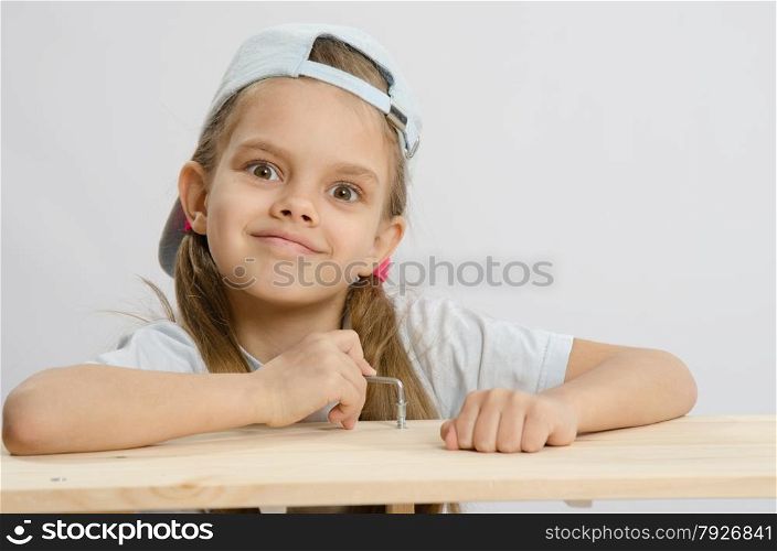 Six year old girl playing and collecting wooden cabinet. Girl likes to twist the screw with an Allen key