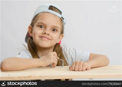 Six year old girl playing and collecting wooden cabinet. Girl likes to twist the screw with an Allen key