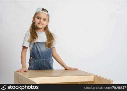 Six year old girl playing and collecting wooden cabinet. Portrait of a child in working clothes carpenter
