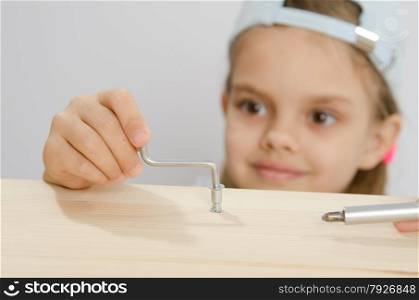 Six year old girl playing and collecting wooden cabinet. Girl in the classroom working spins screw