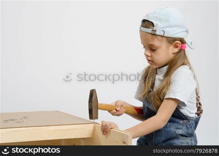 Six year old girl playing and collecting wooden cabinet. Child washes rear wall of the chest