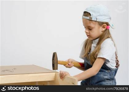 Six year old girl playing and collecting wooden cabinet. Child washes rear wall of the chest