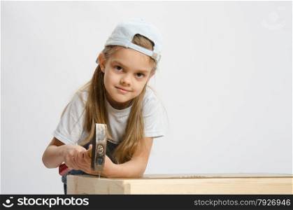 Six year old girl playing and collecting wooden cabinet. Child labor in classroom hammer nails with a hammer