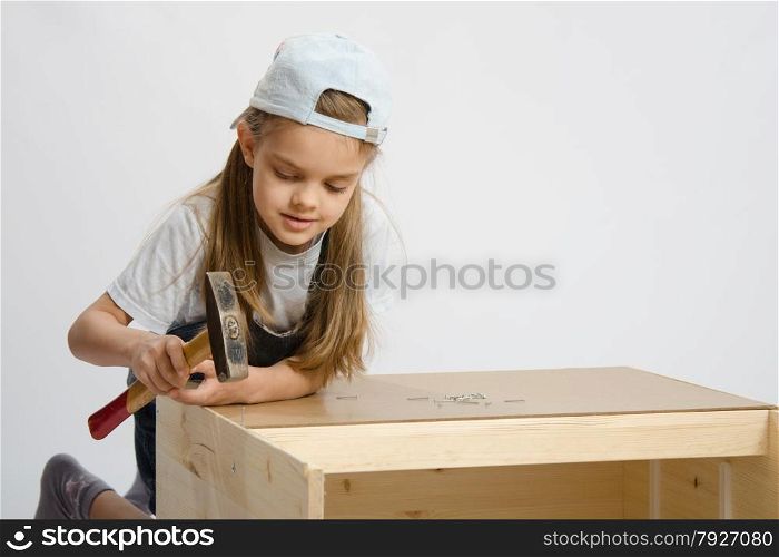 Six year old girl playing and collecting wooden cabinet. Girl in classroom work to hammer nail with a hammer