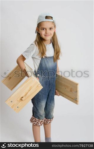 Six year old girl playing and collecting wooden cabinet. Portrait of a six year old girl with boards in hands