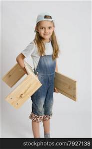 Six year old girl playing and collecting wooden cabinet. Portrait of a six year old girl with boards in hands