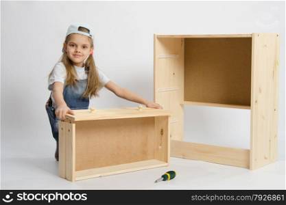 Six year old girl playing and collecting wooden cabinet. child plays in the builder furniture