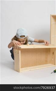 Six year old girl playing and collecting wooden cabinet. Girl collects drawer