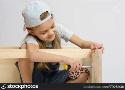Six year old girl playing and collecting wooden cabinet. girl having fun twists screw