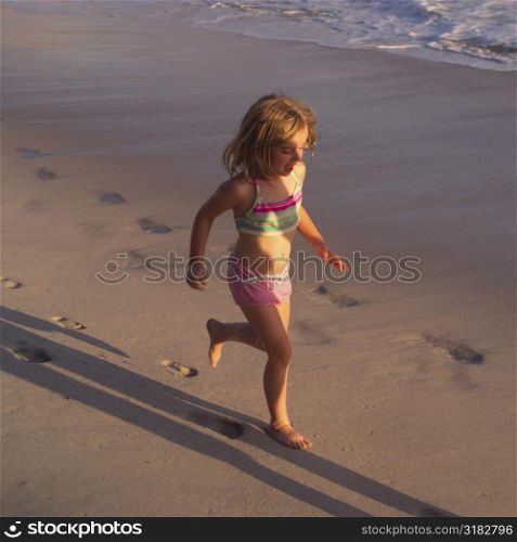 Six year old girl running on the beach